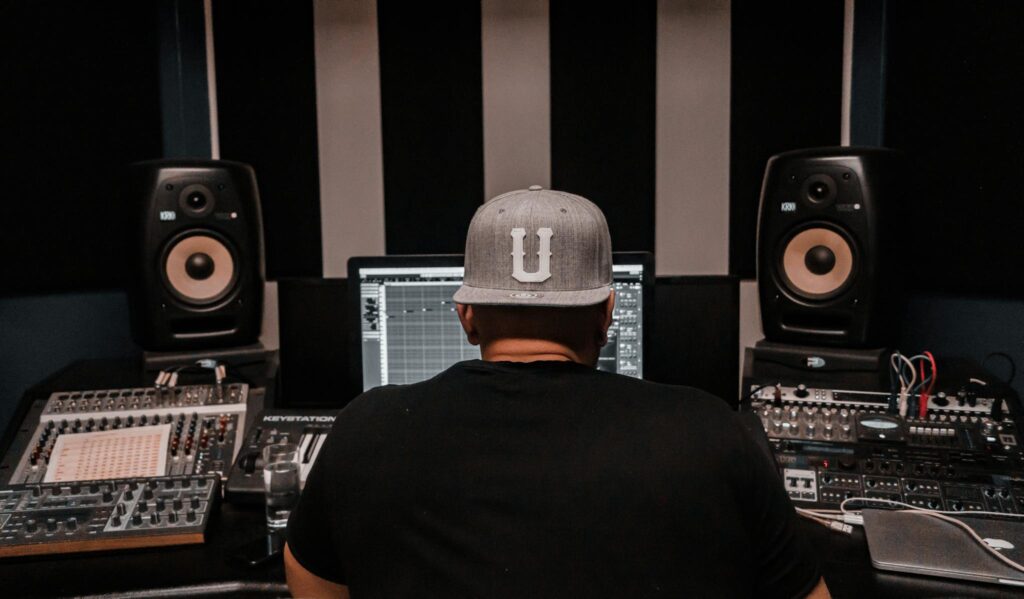 A music producer working in a recording studio surrounded by professional audio equipment.