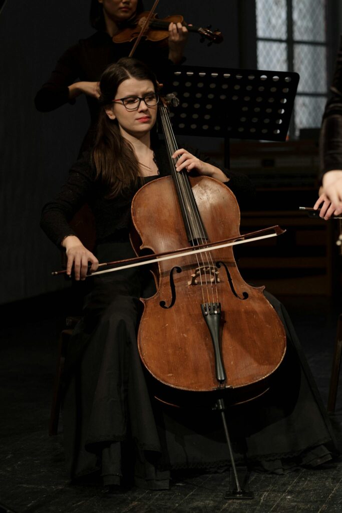 A professional female cellist performing classical music on stage during a concert.